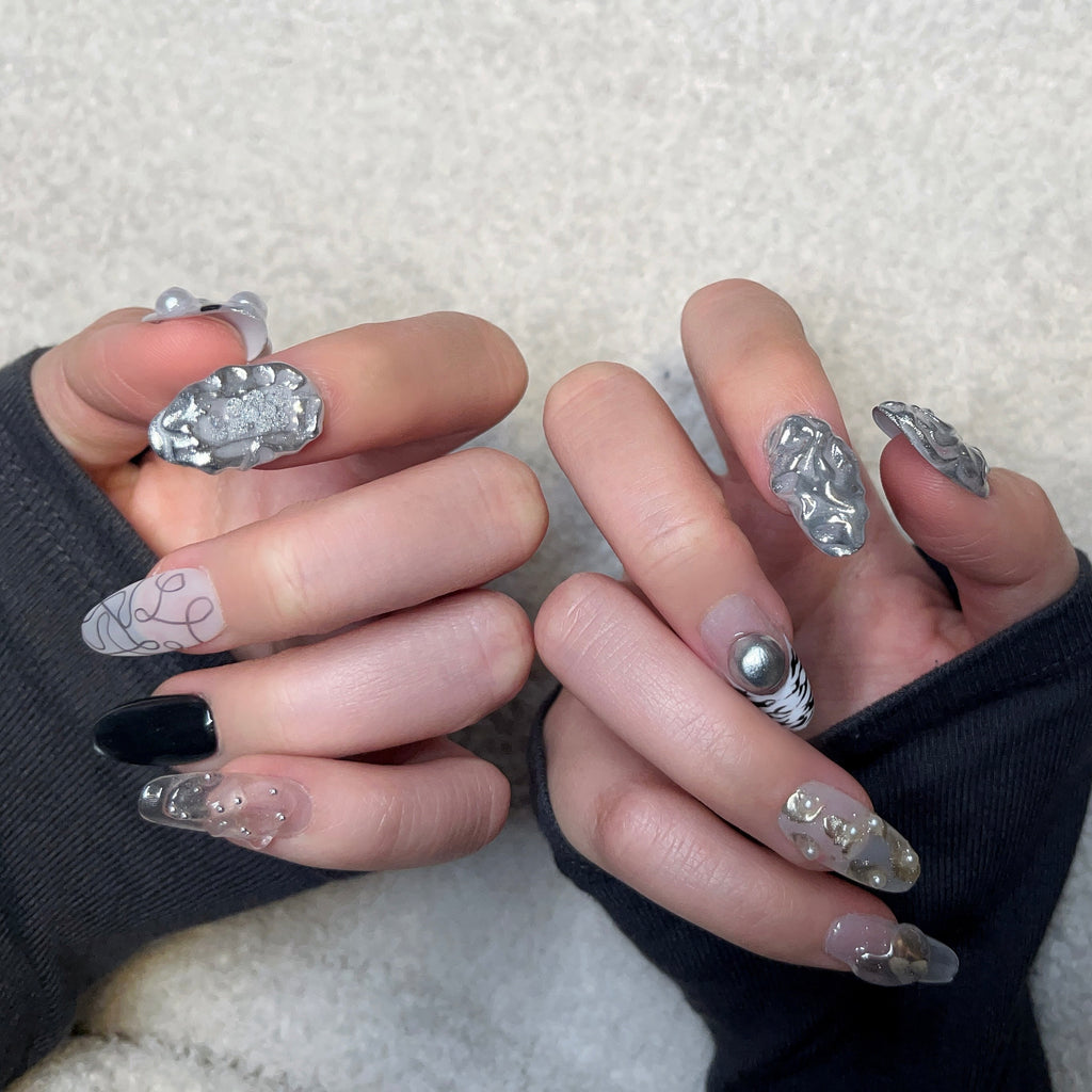 Handmade silver 3D almond press-on nails from Fjaka Nails, second hand model wear shot showcasing raised silver texture, pearls, steel beads, clear base, zebra print, cat eye and abstract swirl designs, salon-quality reusable nails for UK niche industrial aesthetic lovers